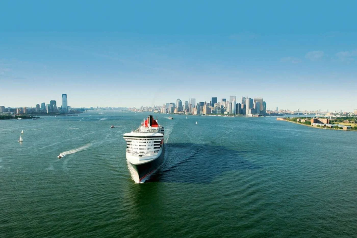 Cruise ship sailing with a city skyline in the distance